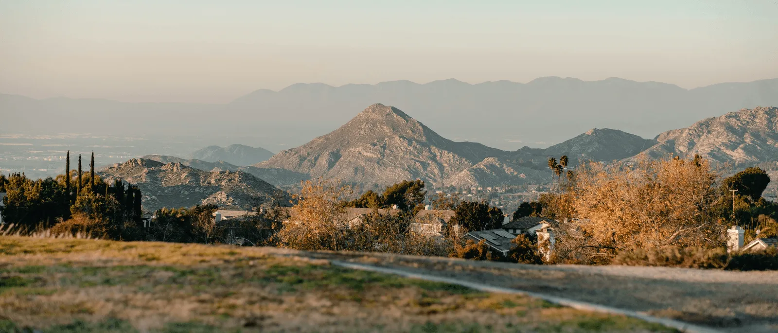 Dry foothills at sunrise, a valley and mountain range in the distance.