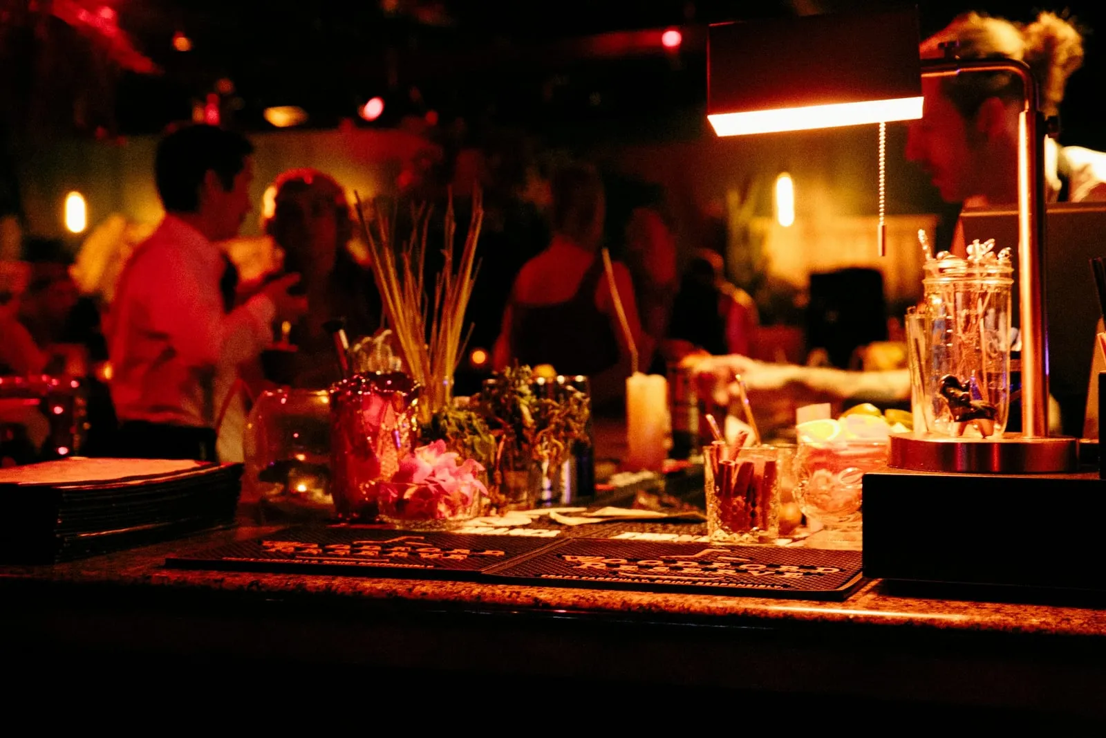 A dimly lit bar at night, glasses and candles along the counter.